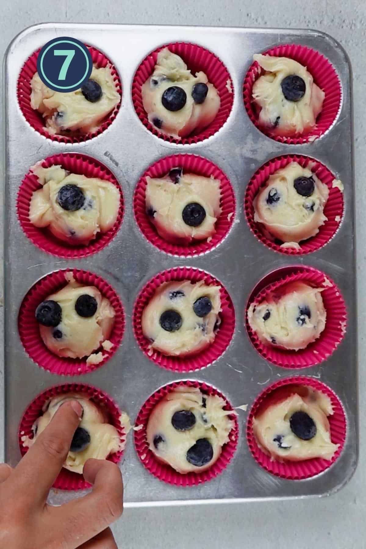 scooping out the blueberry muffin batter into the muffin liners.