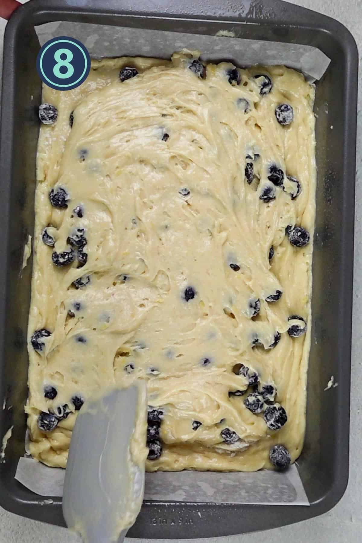 adding the rest of the cake batter over the blueberries.