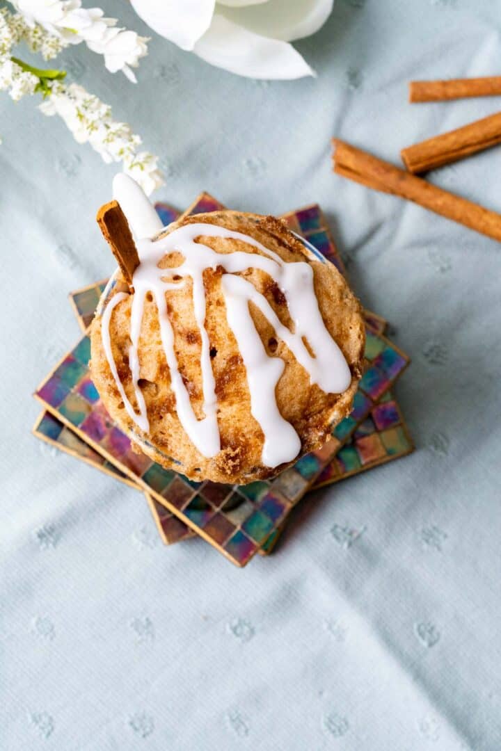 overhead shot of cinnamon roll mug cake with drizzled glaze on the top of the cake.