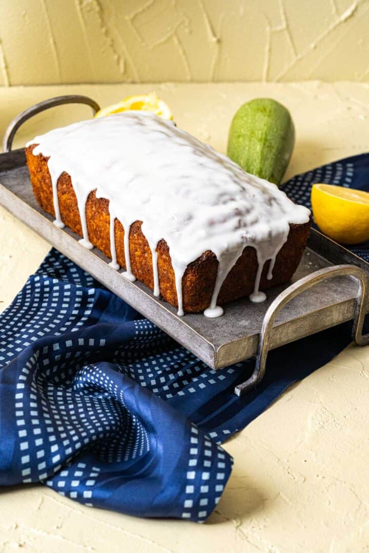 close shot of whole loaf of zucchini and lemon bread on a gray plate.