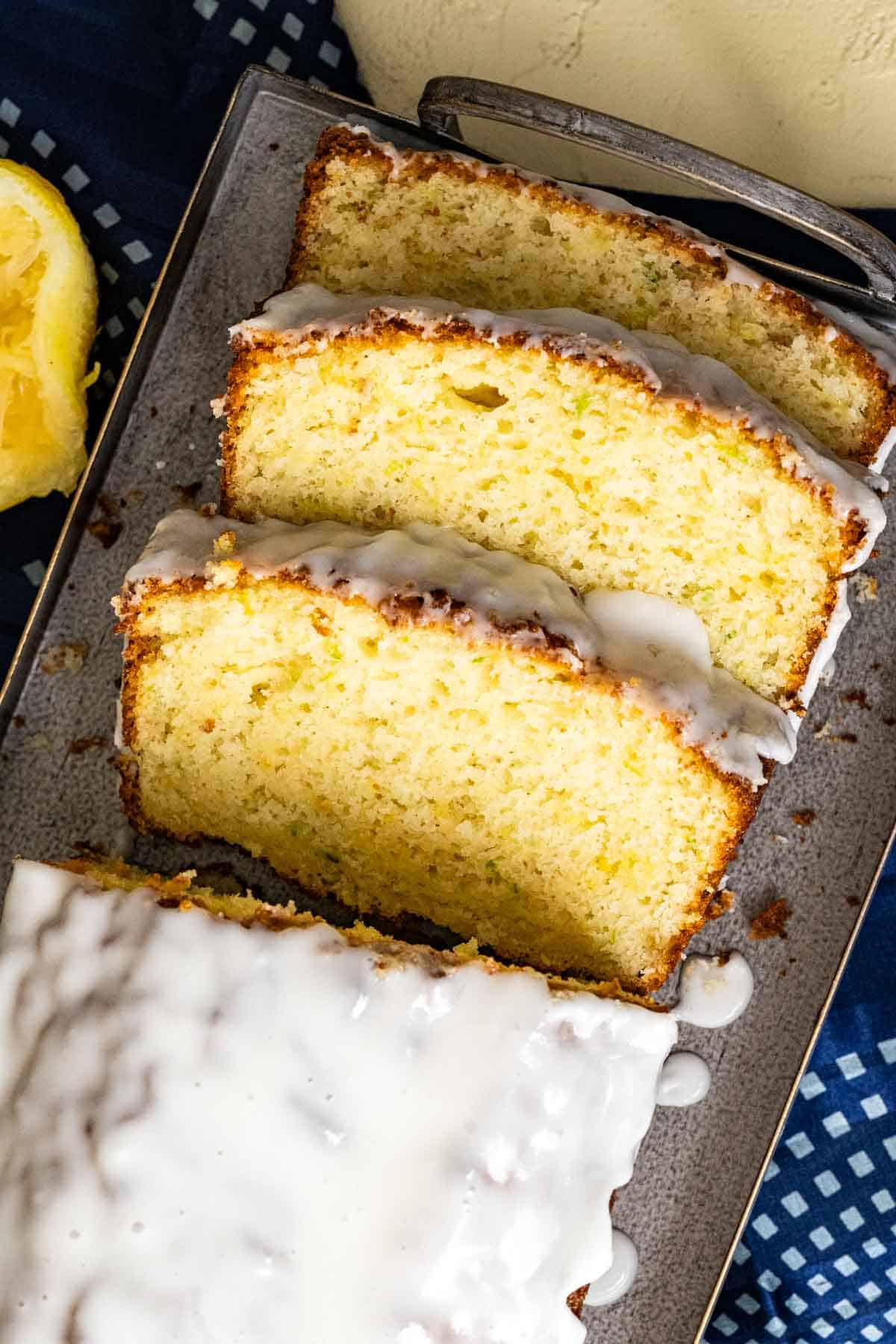 Three slices of lemon and zucchini bread with lemon glaze.