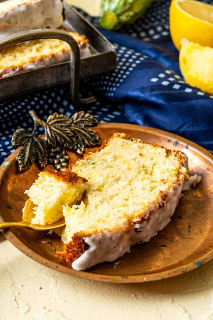 one slice of lemon zucchini bread in a golden antique plate.