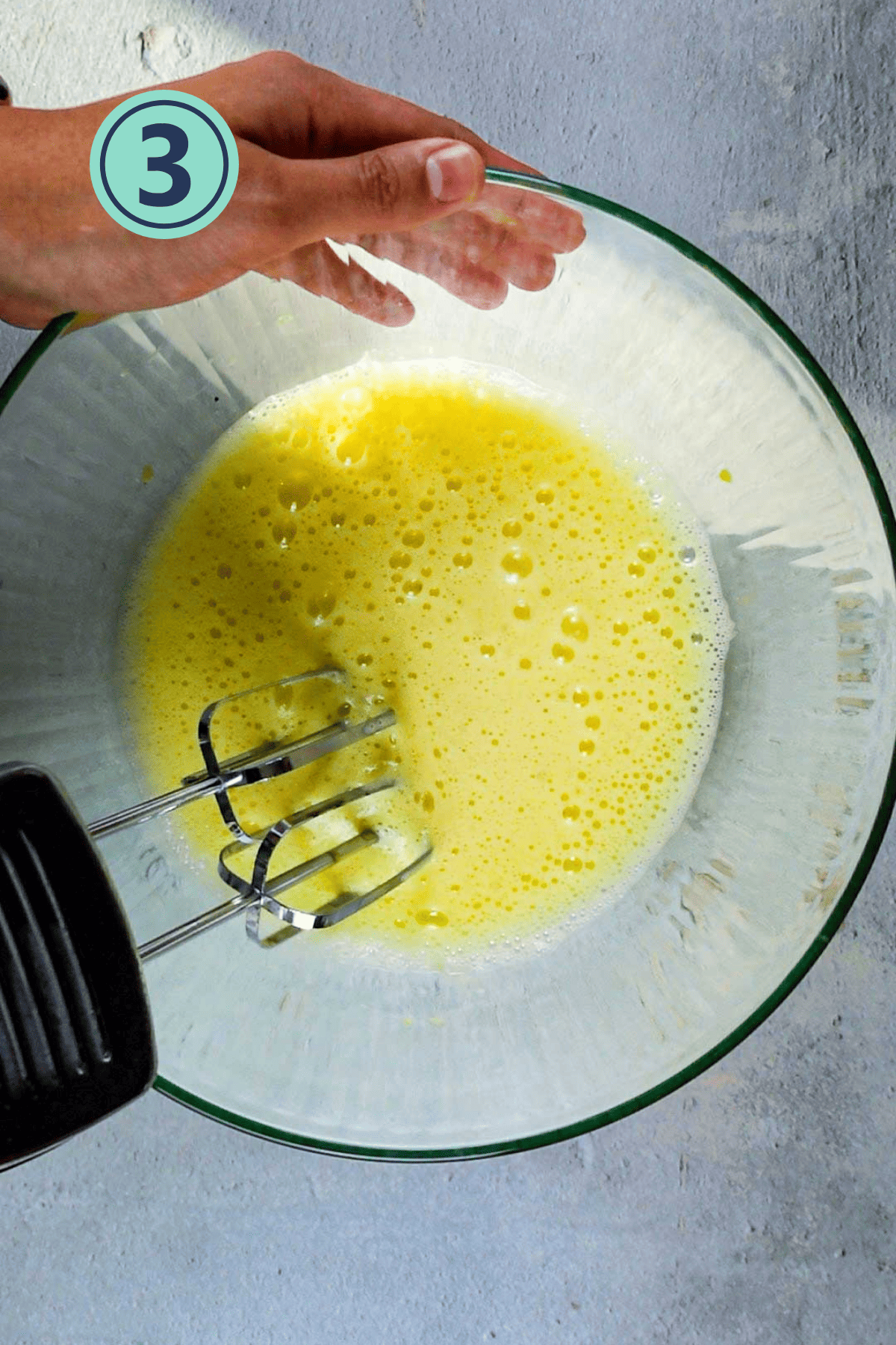 Beating the eggs using an electric beater in a large bowl.