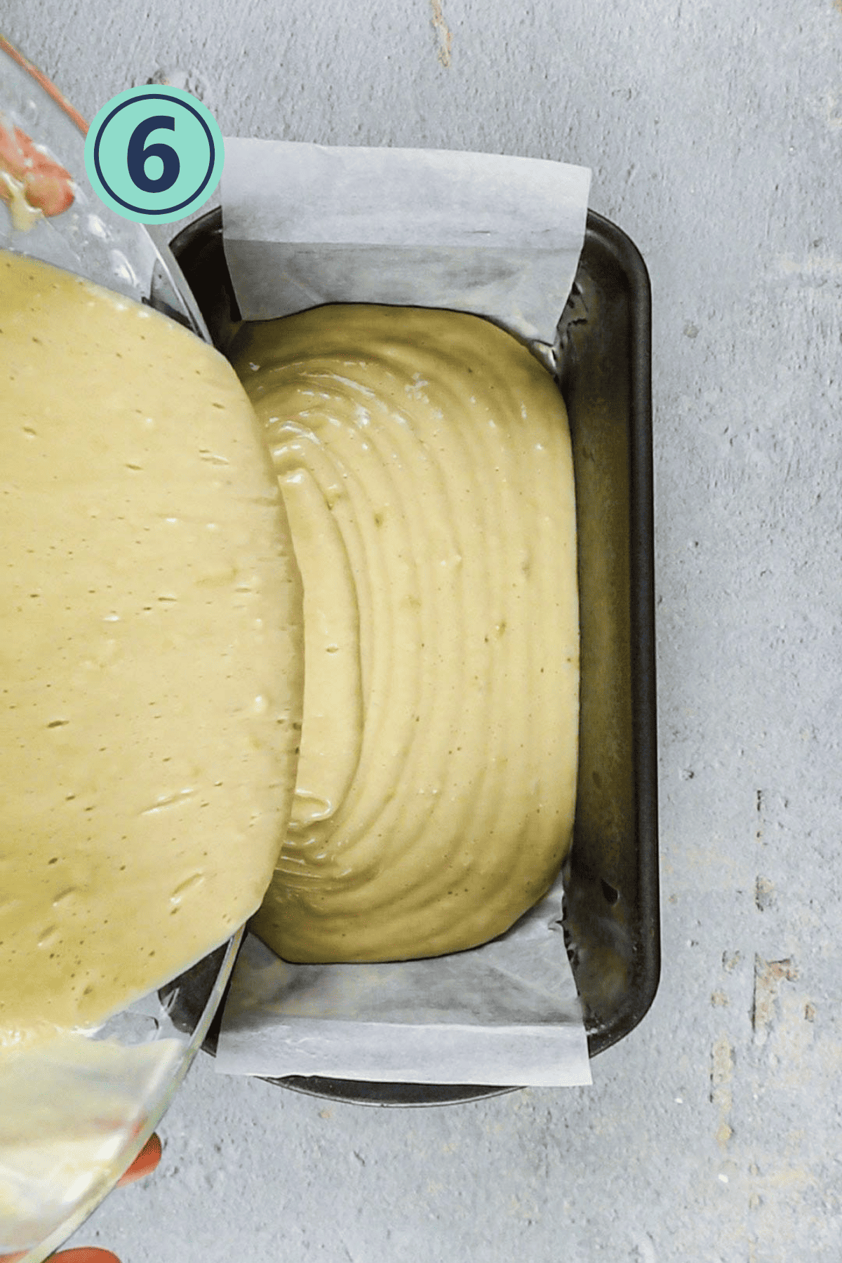 Pouring the cake batter into the greased pan. 