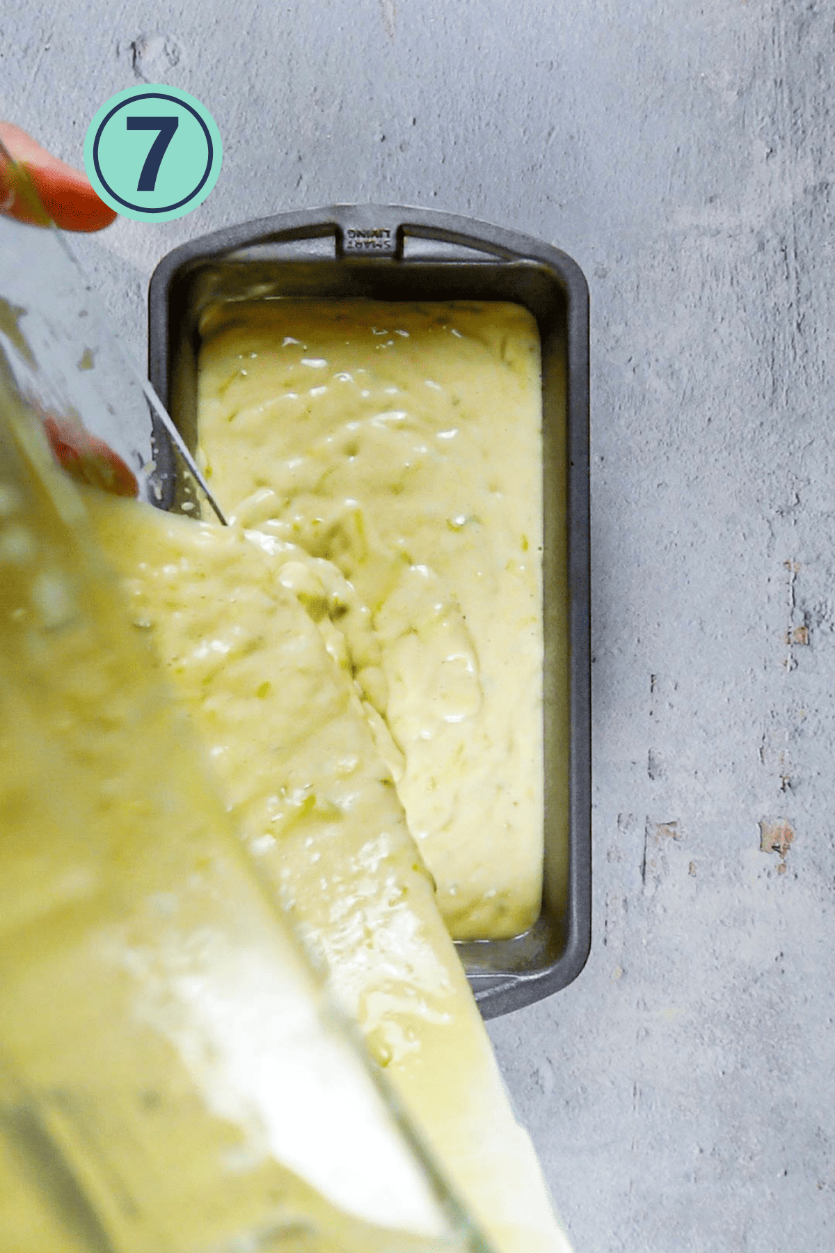 Pouring out the lemon zucchini bread batter into the pan.