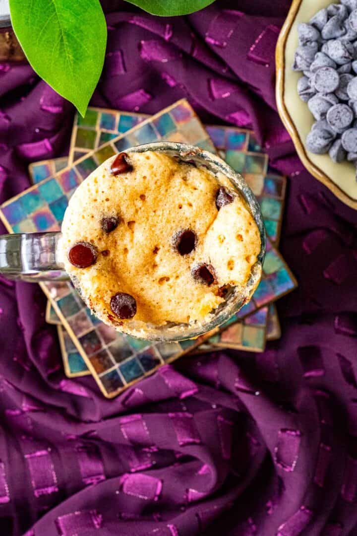 overhead shot of chocolate mug cake sitting on a magenta table cloth.