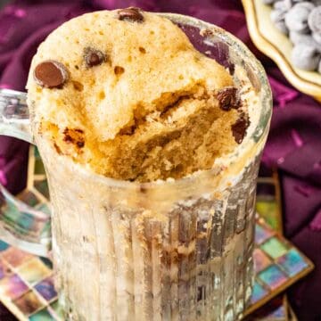 mug cake in a transparent mug with chocolate chips sprinkled on the top.