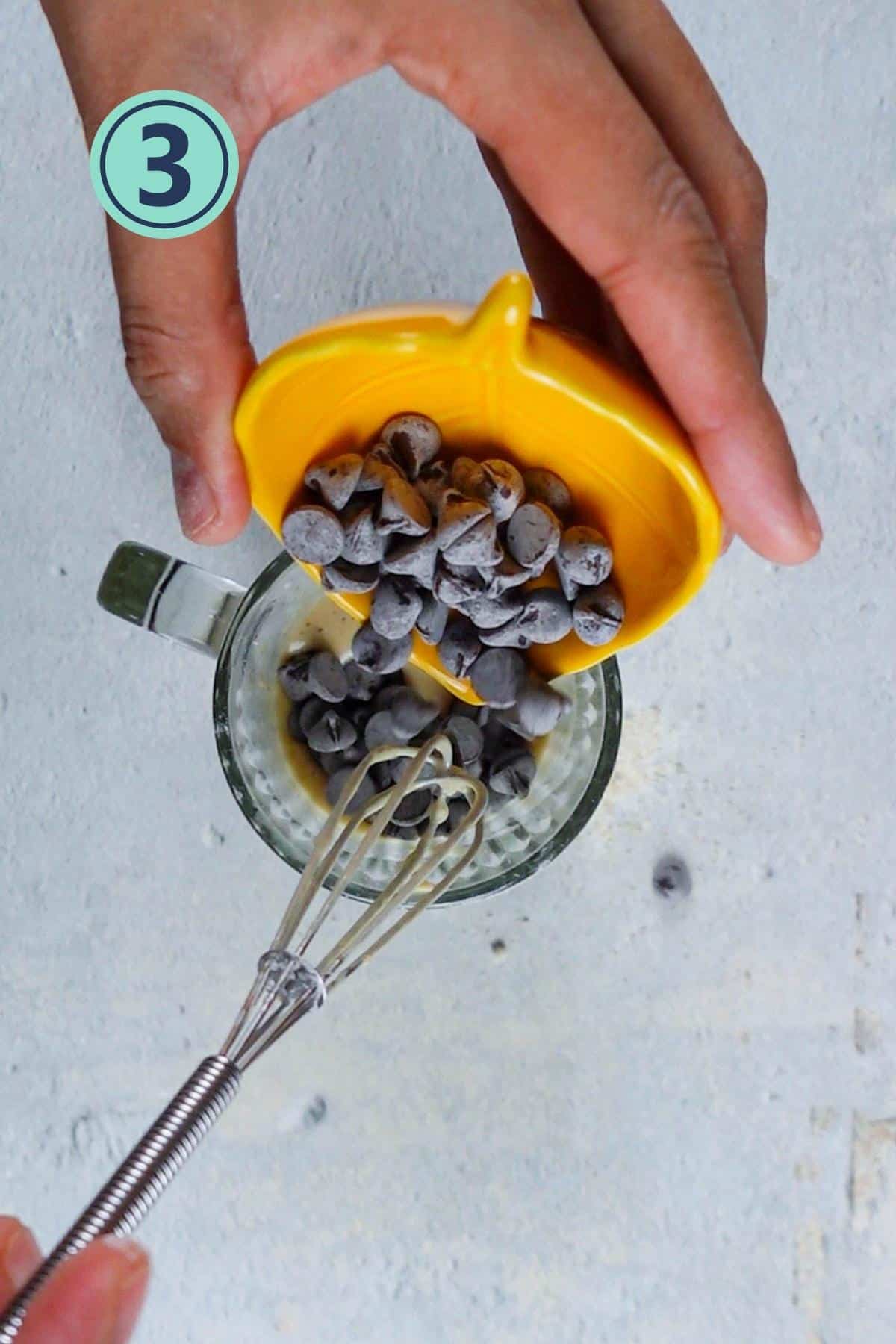 Adding chocolate chips to the mug cake batter.