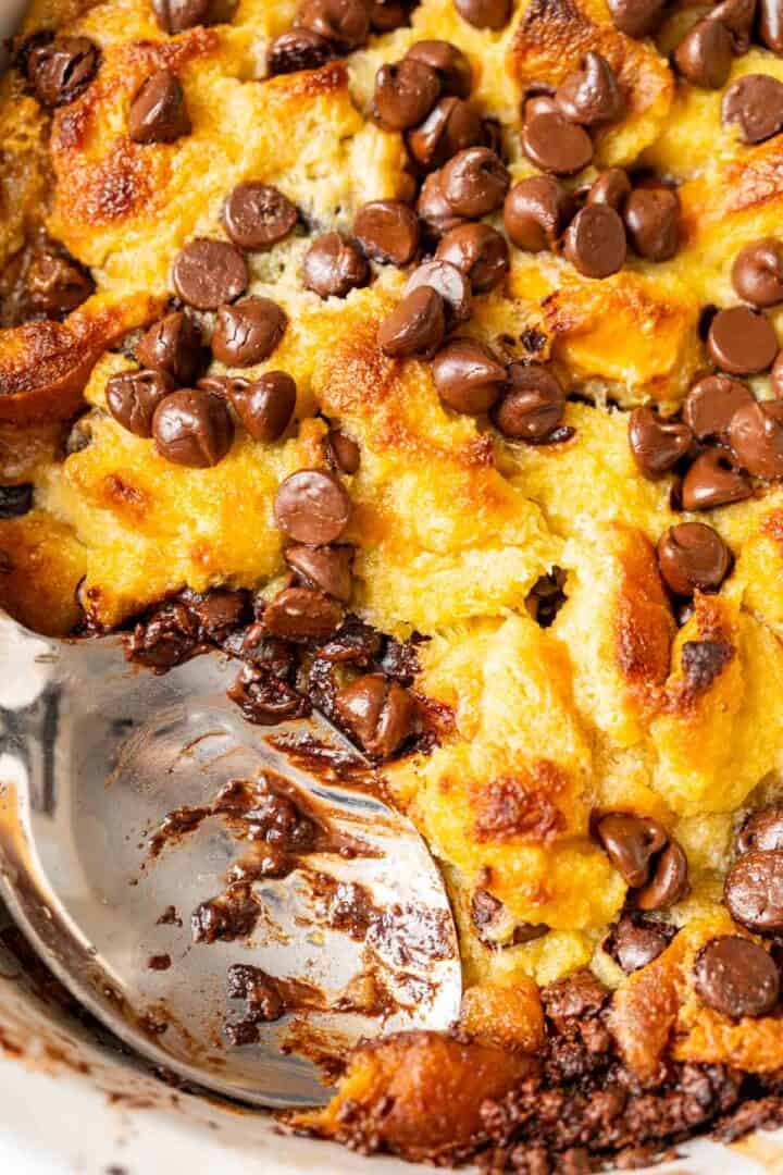 Chocolate chip pudding with a silver spoon in a white bowl.